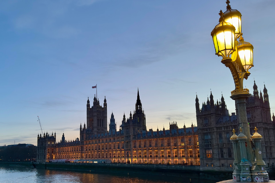 The Houses of Parliament in Westminster, London at dusk with an historic lamp on Westminster Bridge in the foreground. - stock photo
