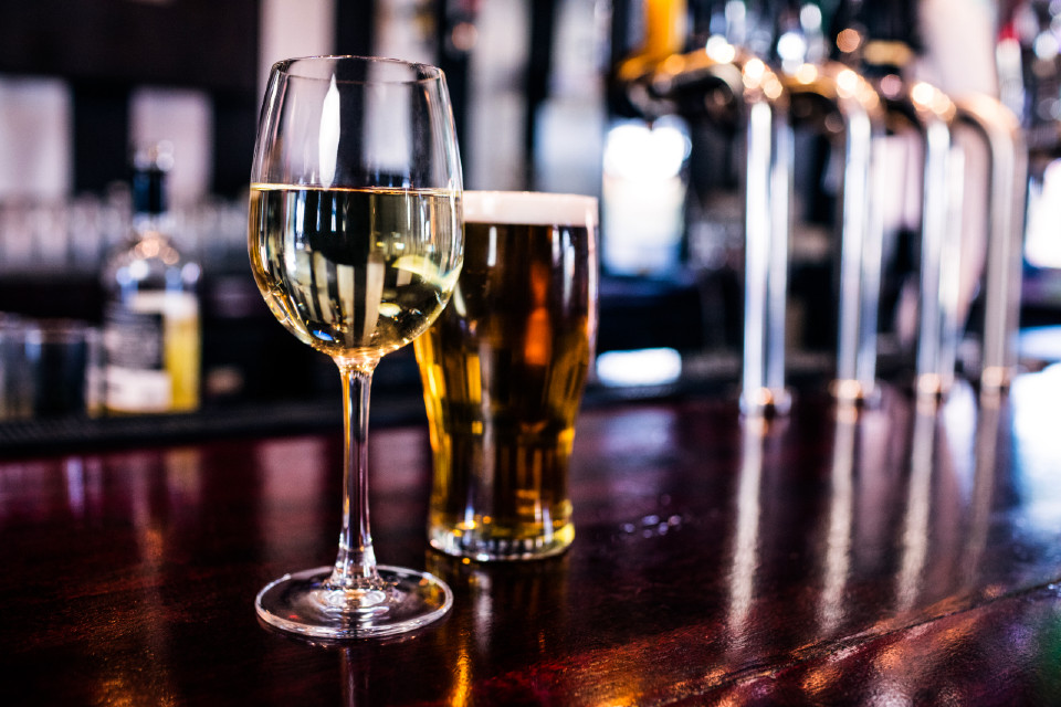 Glass of wine and pint of beer on a bar
